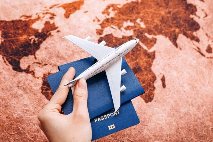 Hand holding NEUTURAL passport on the world map background with model airplane / travel concept / selective focus Visa-Free Countries for Indian Travelers 2025