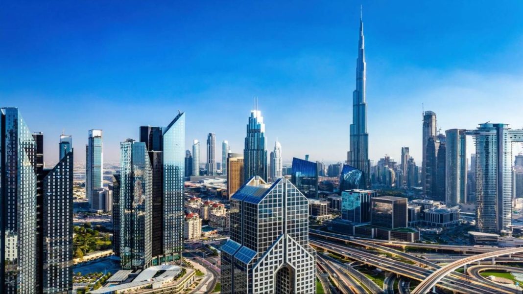 Beyond Burj Khalifa: Dubai Attractions That Deserve Your Attention Modern Dubai skyline featuring tall glass skyscrapers, intersecting highways, and the Burj Khalifa rising prominently under a clear blue sky.